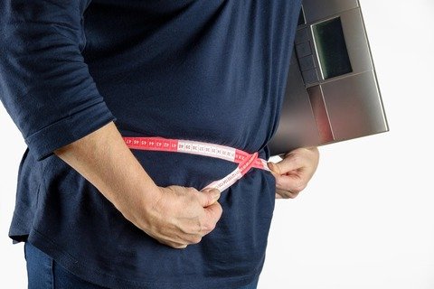 Person measuring waistline with tape measure
